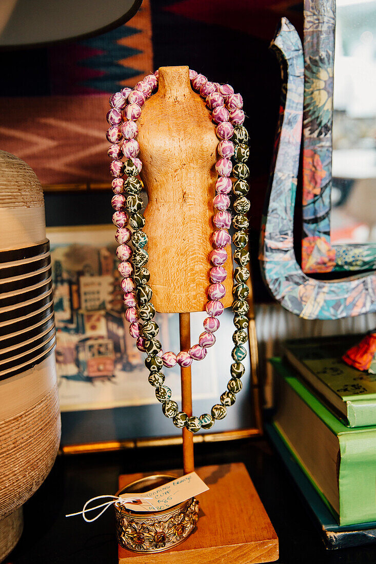 Necklaces draped over mannequin stand