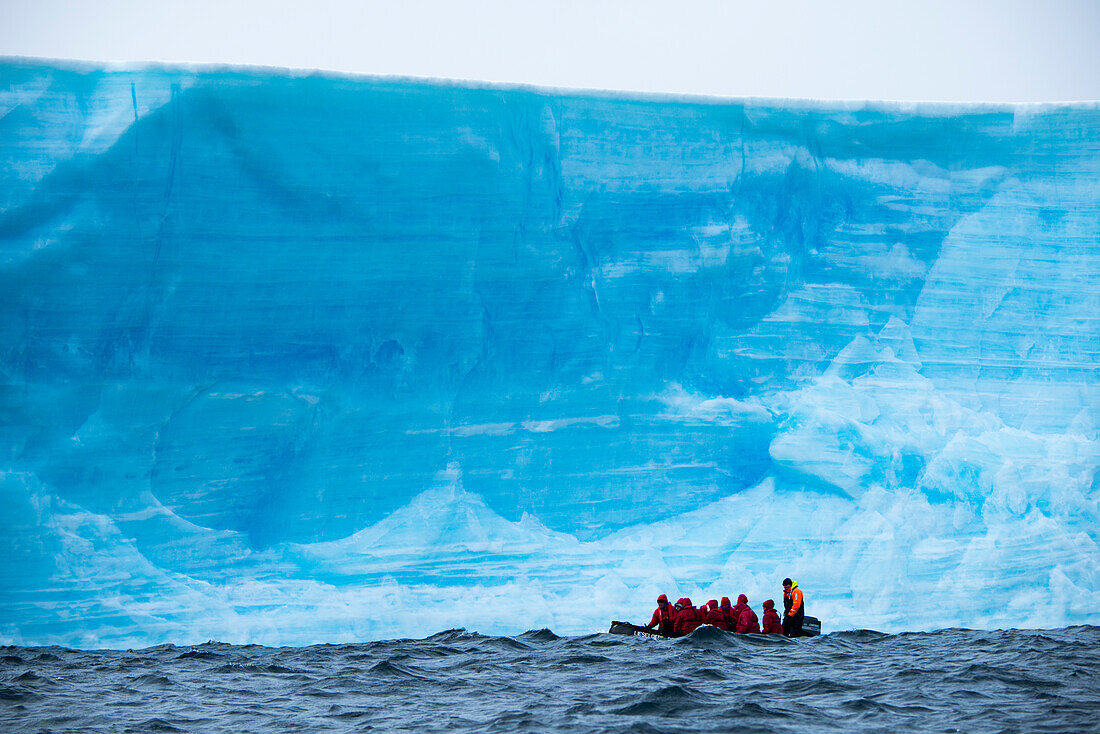 Groessenunterschied: Zodiac Schlauchboot von Expeditions-Kreuzfahrtschiff MS Hanseatic Hapag-Lloyd Kreuzfahrten vor Eisberg, nahe Suedliche Orkneyinseln, Antarktis