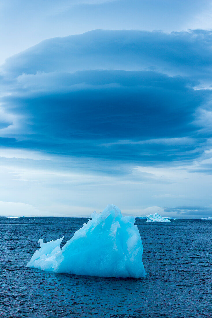 Contrasting forms: A ragged blue iceberg and a softly rounded blue cloud formation , Paulet Island, Antarctic Peninsula, Antarctica
