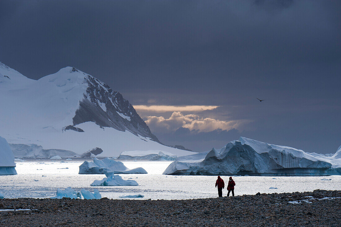 Passagiere von Expeditions-Kreuzfahrtschiff MS Hanseatic Hapag-Lloyd Kreuzfahrten trekken durch Schnee und felsiger Landschaft suedlich vom Polarkreis, Stonington Island, Antarktische Halbinsel, Antarktis