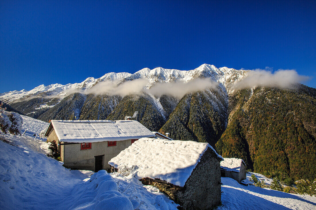 Mountain houses framed by snowy peaks, San Salvatore, Livrio Valley, Orobie Alps, Valtellina, Lombardy, Italy, Europe