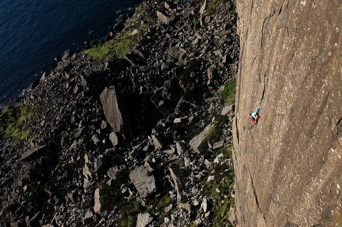 A climber scales the 100 metre cliffs at Fair Head, County Antrim, Ulster, Northern Ireland, United Kingdom, Europe