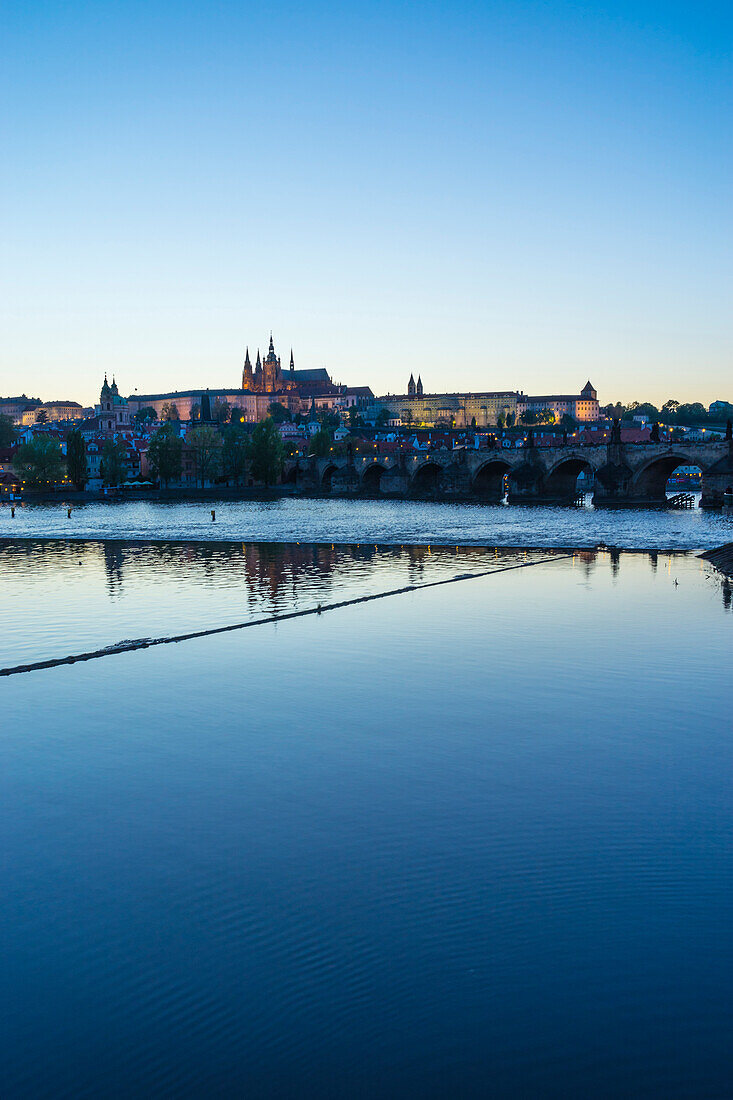 View of Charles Bridge, the Castle District and St. Vitus's Cathedral across the Vltava River at sunset, Prague, Czech Republic, Europe