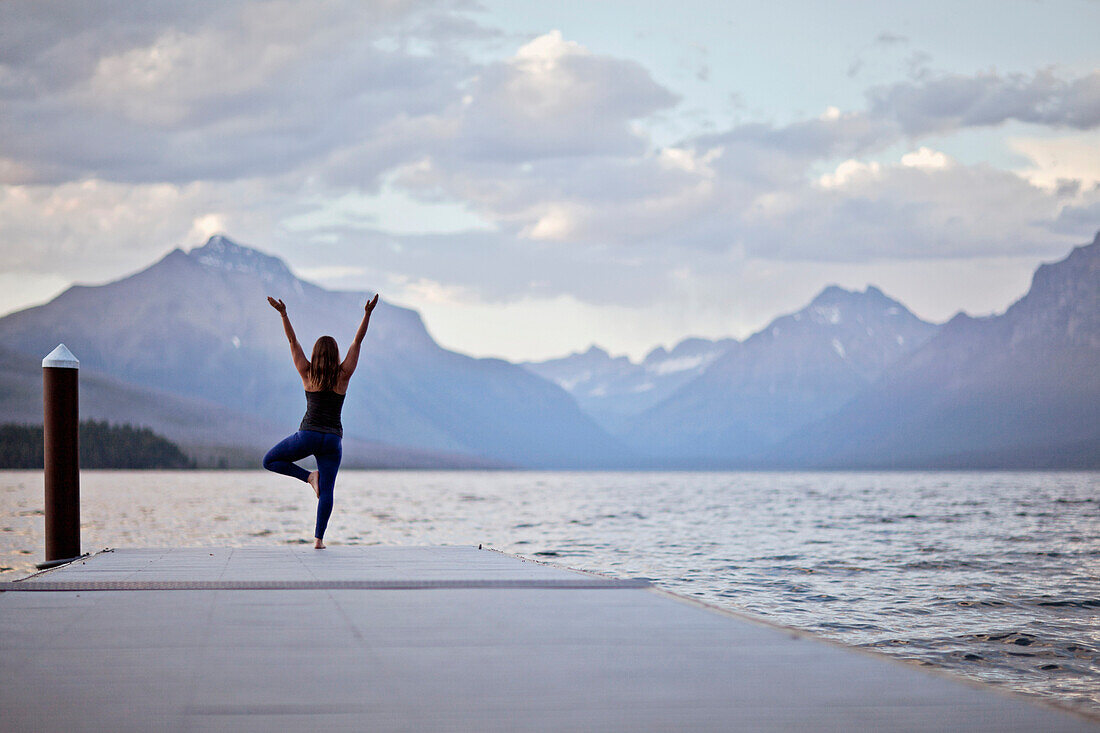 A woman does yoga on a dock in Glacier National Park, Montana.