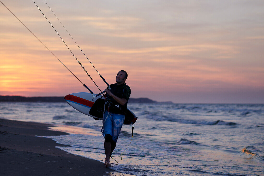 Man waking on the beach with his kitesurfing equipement.