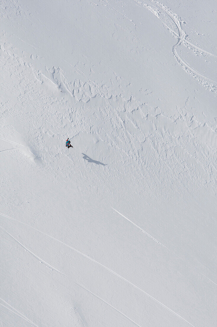 Snowboarder grabbing his board during a late run in Romania at Balea Lake in April