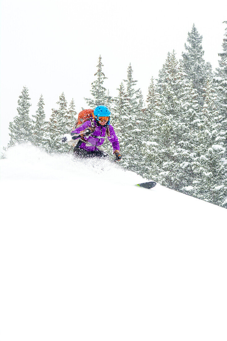 A woman backcountry skiing on a snowy day above Red Mountain Pass in the  Uncompahgre National Forest, Silverton, Colorado.