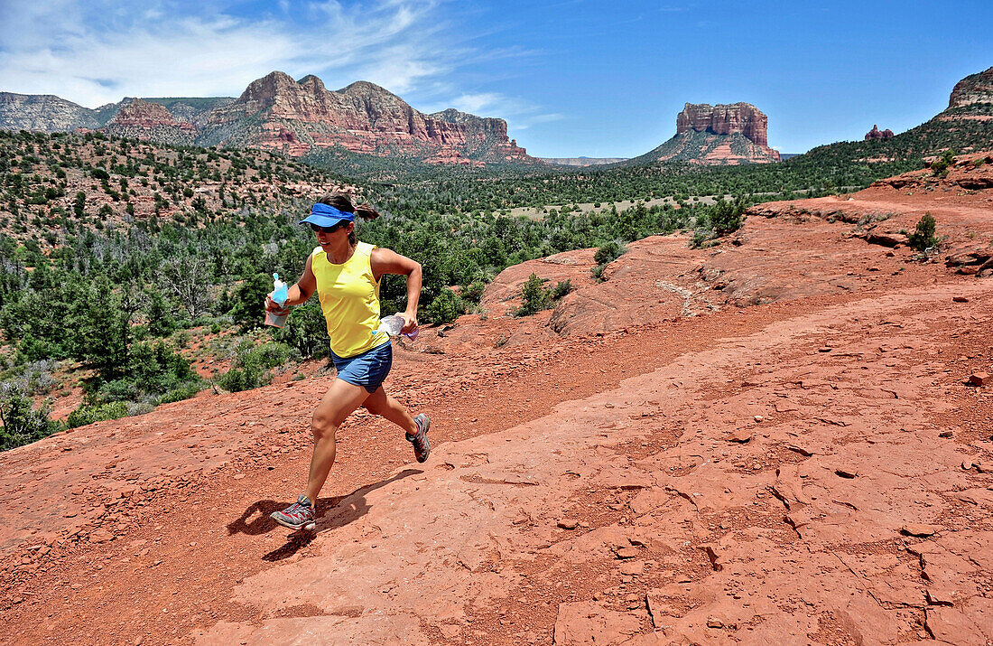 Woman runs the Cathedral Rock Trail in Sedona, Arizona May 2011. The trail over slick rock sandstone leads to a popular group of spires above Sedona.  Model Release: Agnes Hage
