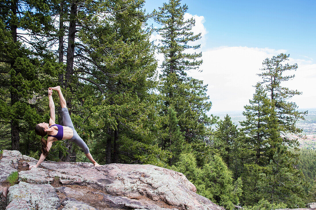 Strong and flexible woman practices yoga on the rocks in Boulder, Colorado