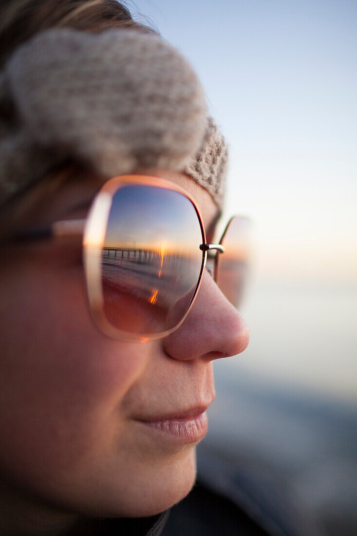 Portrait of a young woman wearing sunglasses at sunset, BC, Canada.