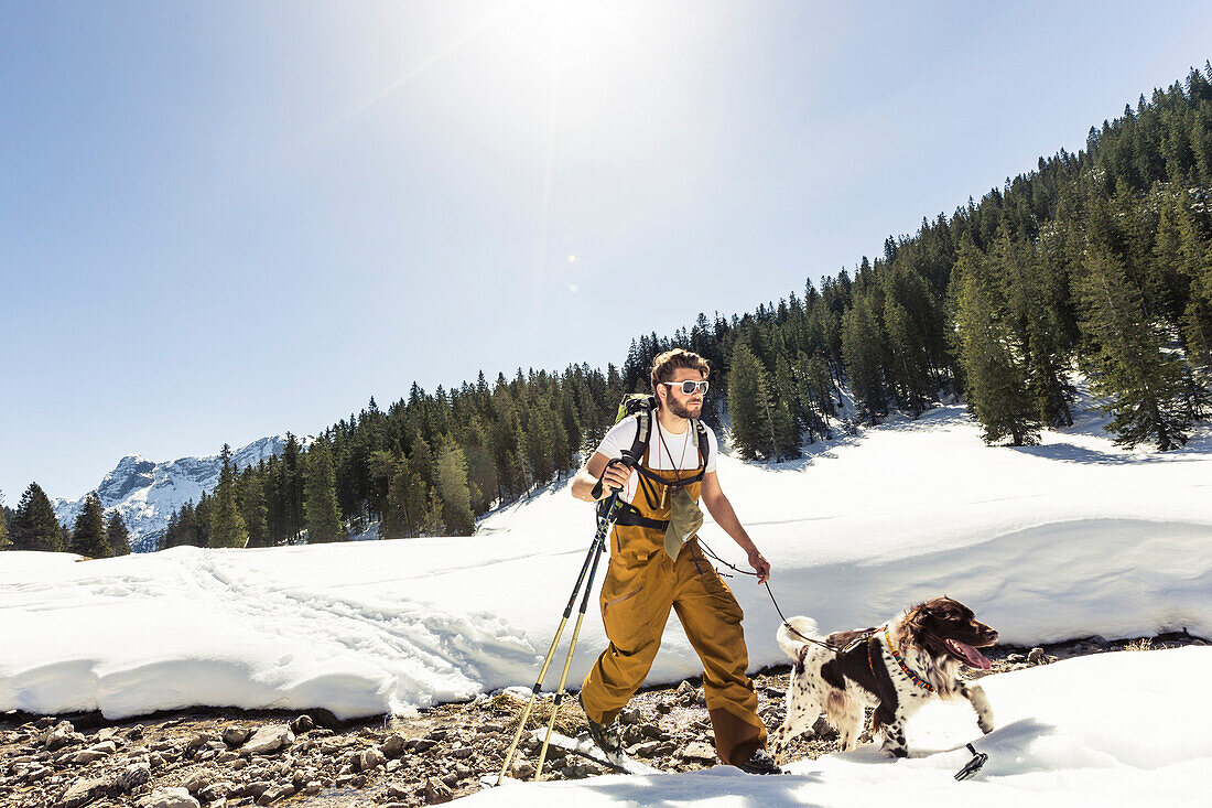 Ski tourer with his dog in the Ammergauer Alps, Bavaria, Germany