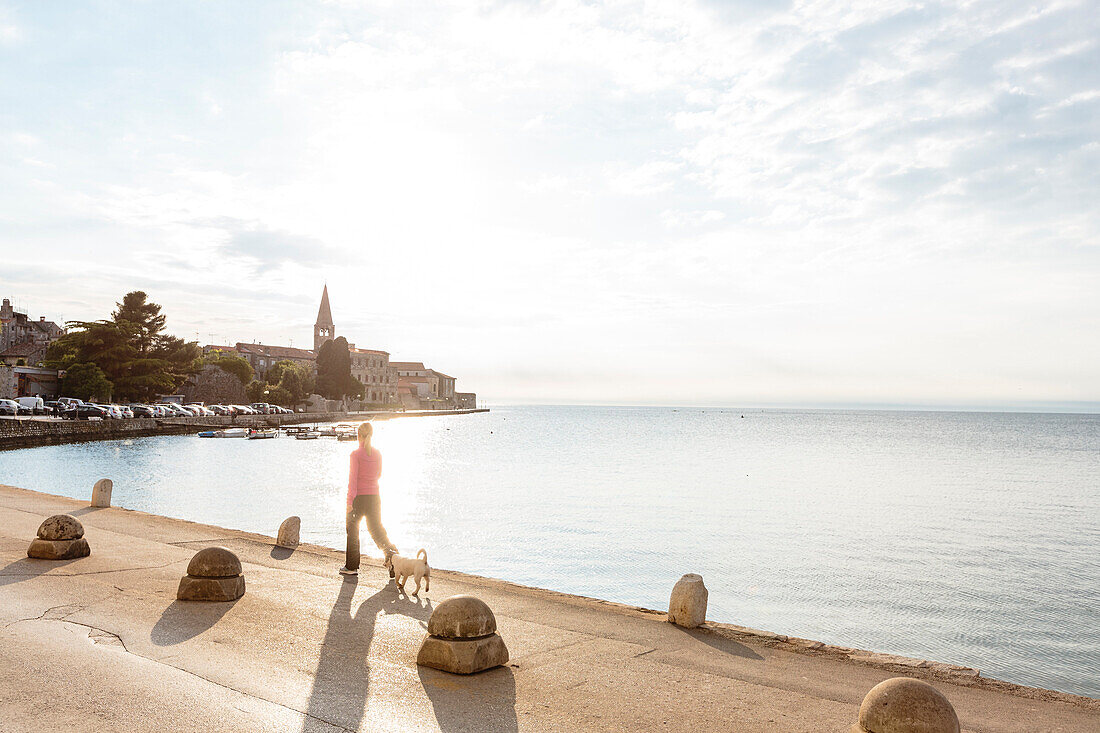 woman and dog walking along the waterfront of Porec, Istria, Croatia