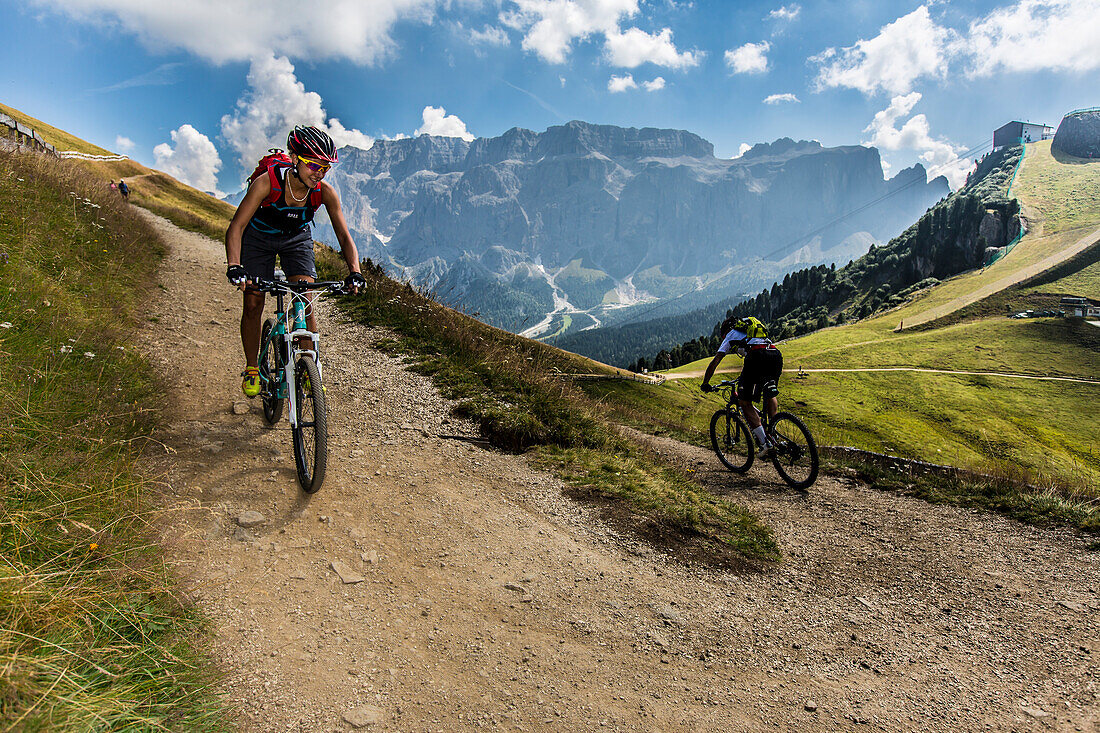 Mountain biker couple at the Ciampinoi, behind it Sella Group, Trentino South Tyrol, Italy