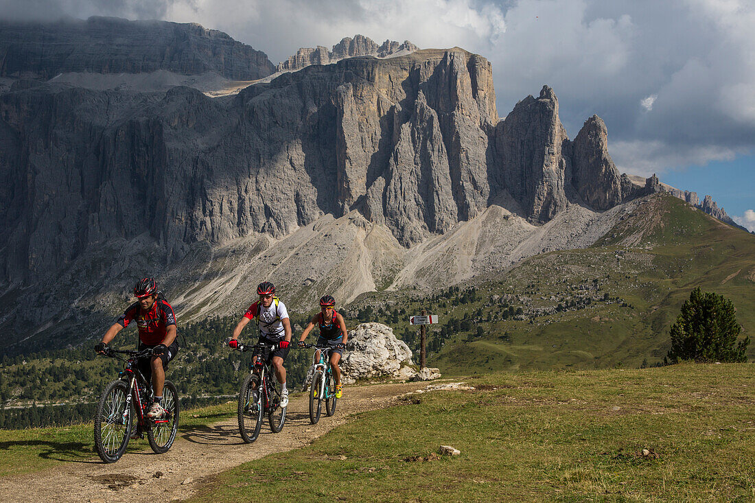 Mountain bikers in the Langkofel area behind it Sella group, Trentino South Tyrol, Italy