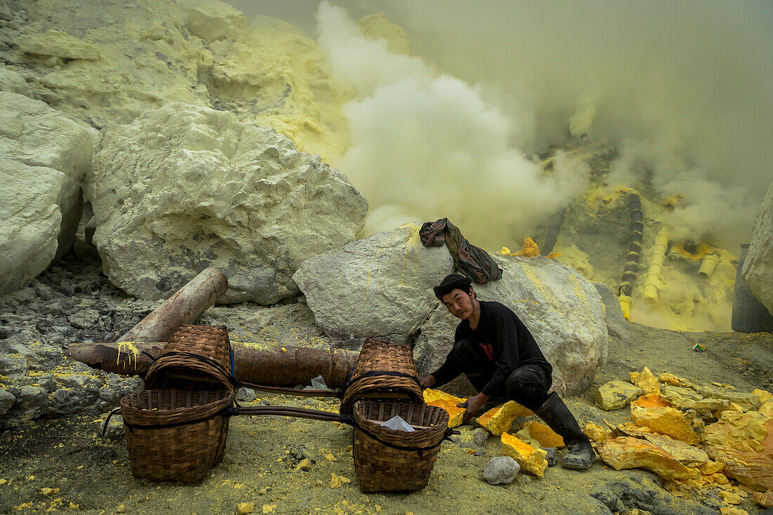 Mienenarbeiter in der Teufelsmine des Vulkan Ijen beim Beladen der Transportkörbe mit Schwefel - Indonesien, Java