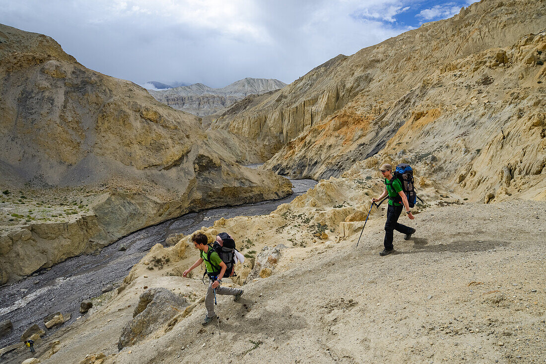 Young men, hikers, trekkers in the surreal landscape typical for Mustang in the high desert around the Kali Gandaki valley, the deepest valley in the world, Mustang, Nepal, Himalaya, Asia