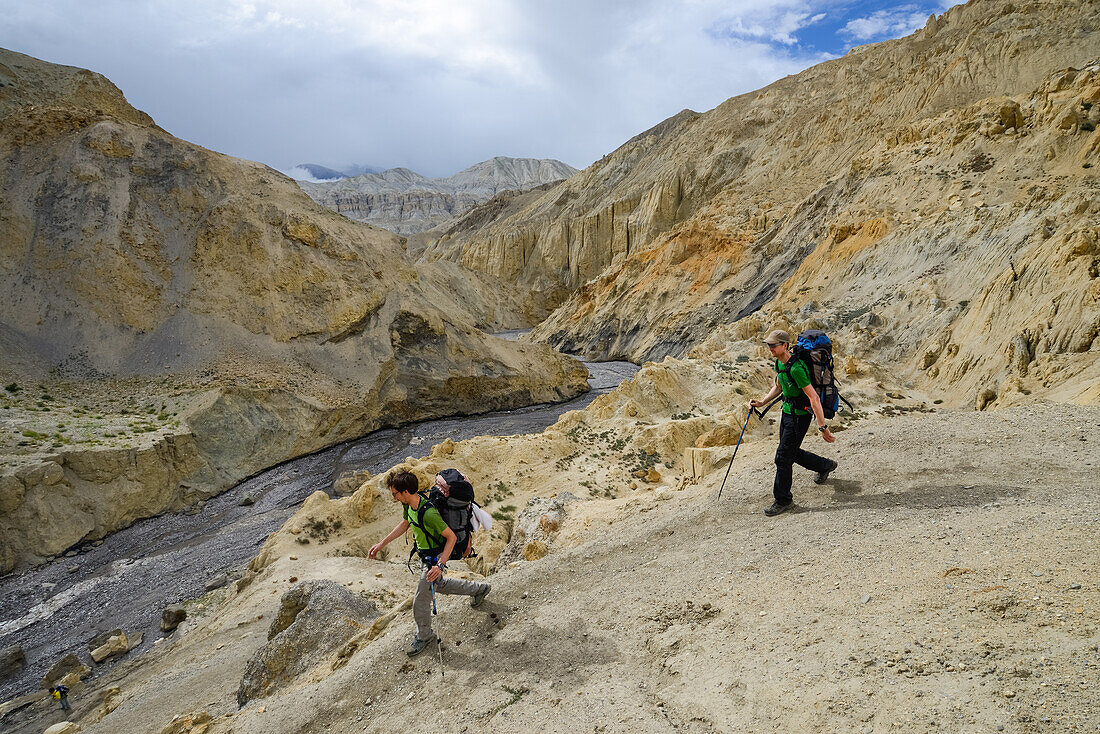 Zwei junge Maenner, Wanderer, Trekker in surrealer Landschaft typisch fuer das Mustang in der Hochwueste um das Kali Gandaki Tal, dem tiefsten Tal der Welt, Mustang, Nepal, Himalaya, Asien