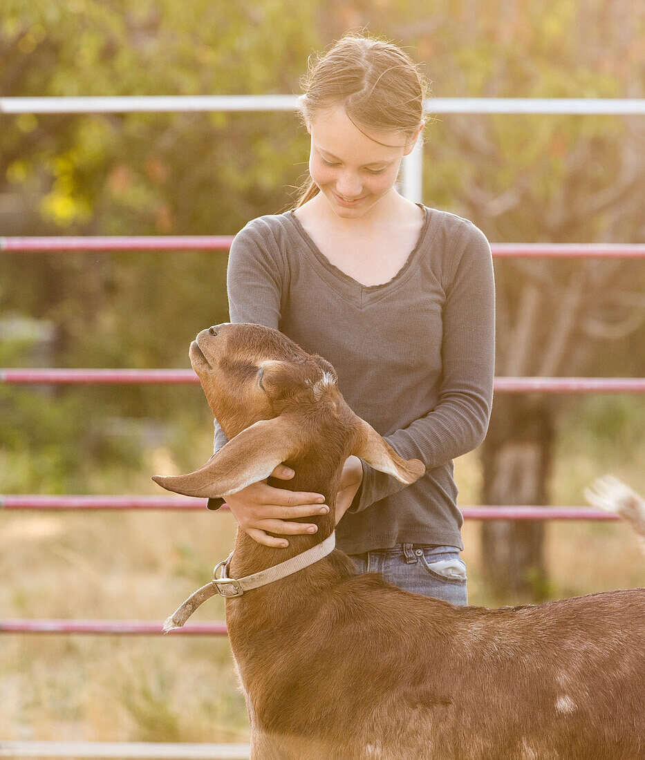 Smiling girl hugging goat on farm