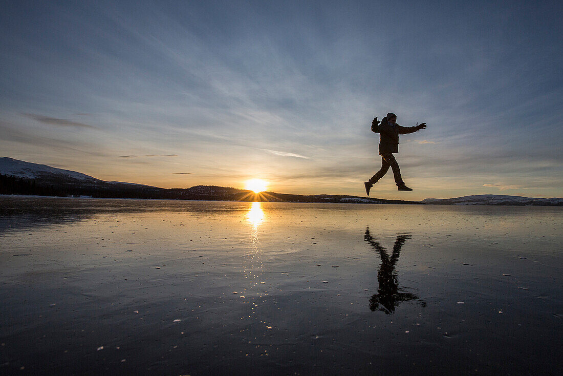 Hiker jumps on the frozen surface of Lake Limingen, Rorvik, Borgefjell National Park, Trondelag, Norway, Scandinavia, Europe