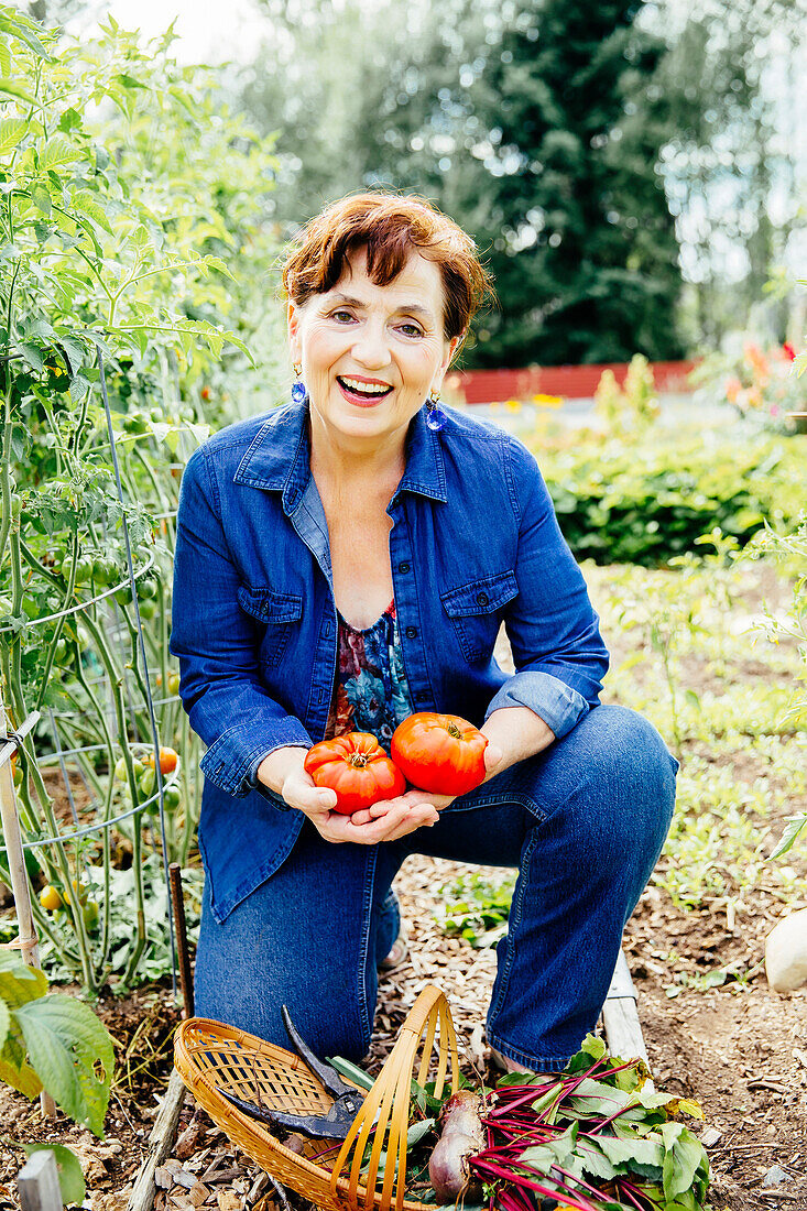 Kaukasische Frau hält Tomaten im Garten