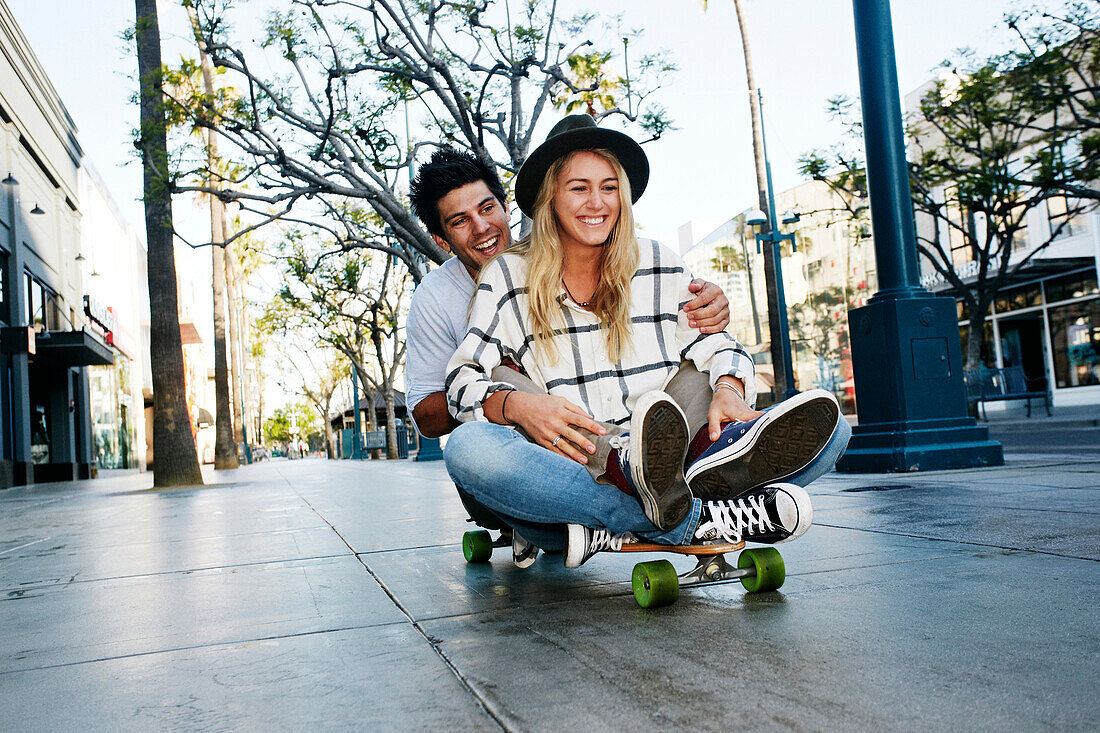 Kaukasisches Paar fährt Skateboard