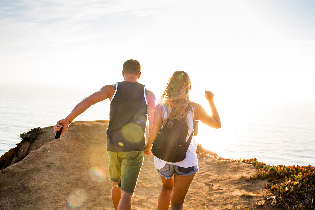 Caucasian couple walking on cliff