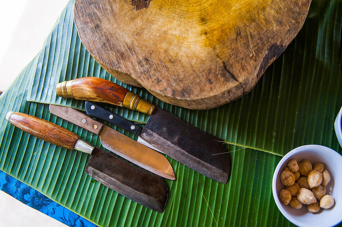 Knives, cutting board and banana leaves on counter