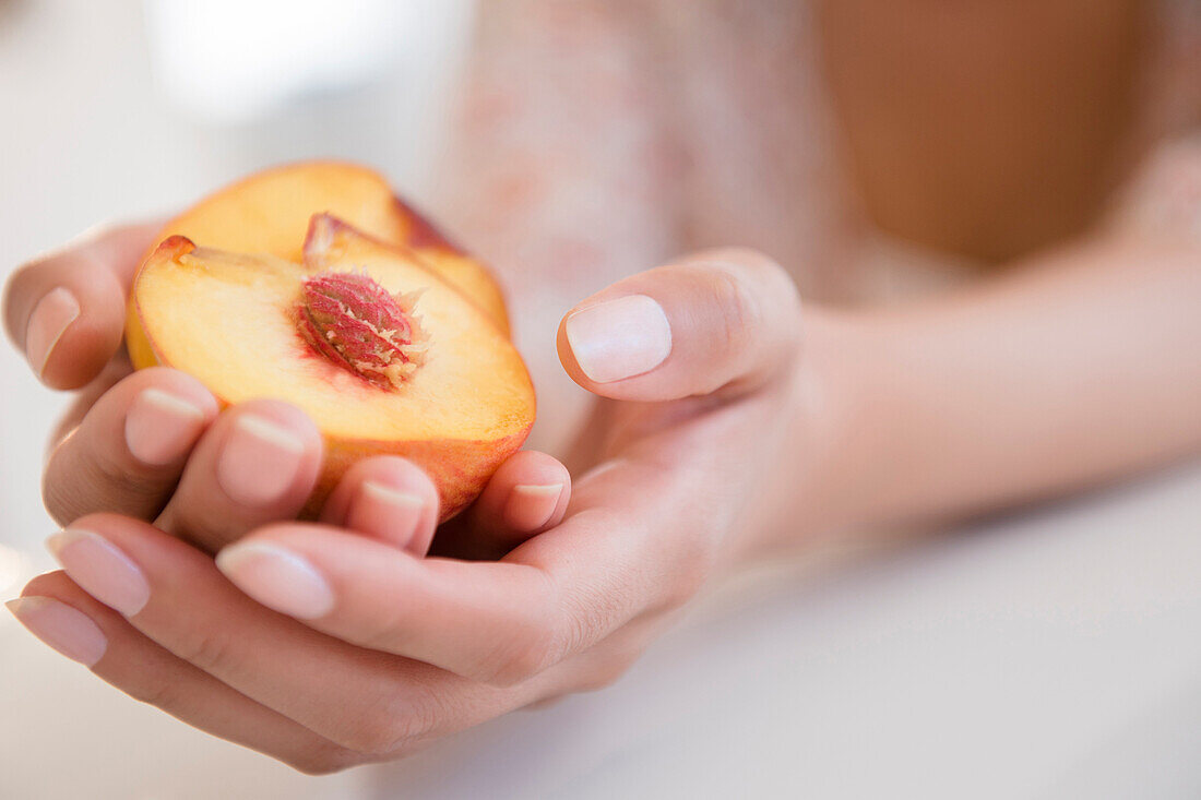 Hispanic woman holding halved peach