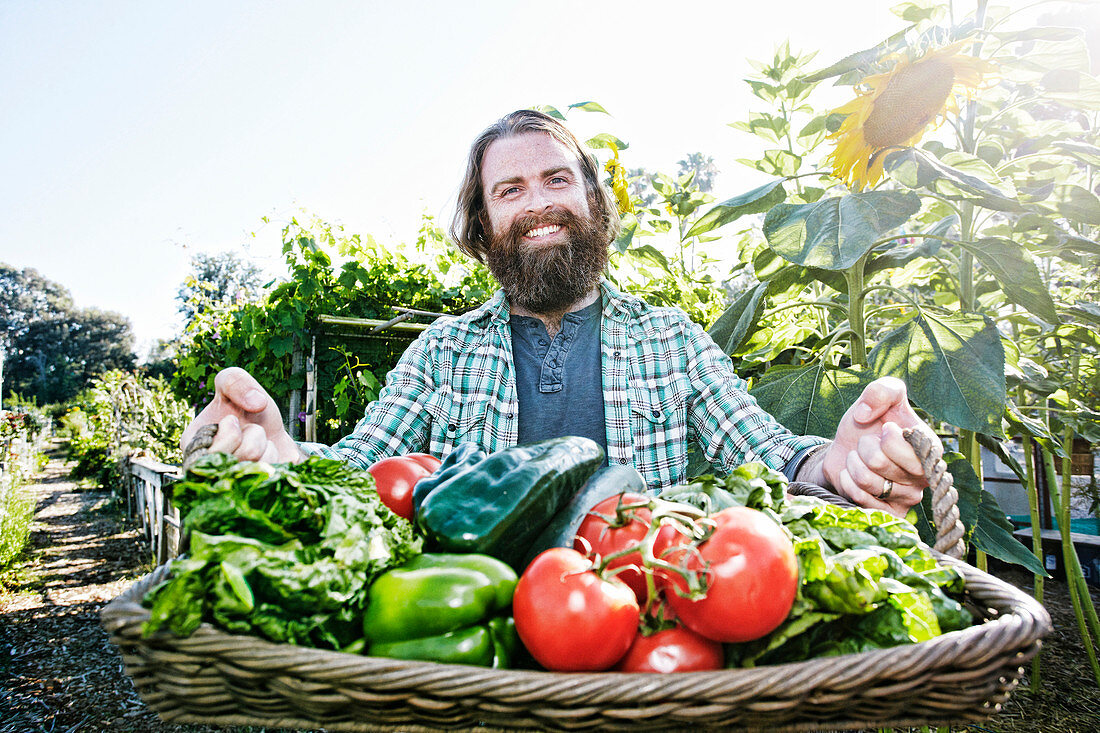 Caucasian man holding basket of vegetables in garden