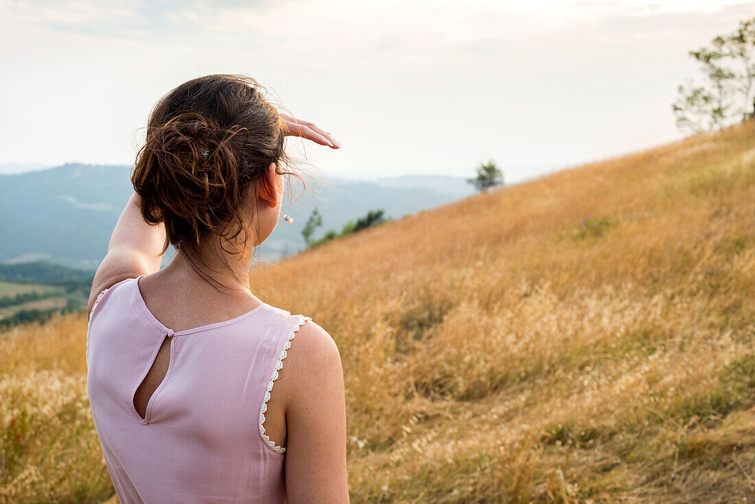 Close-Up of Woman in Pink Dress looking off into Distance in Field, Rear View