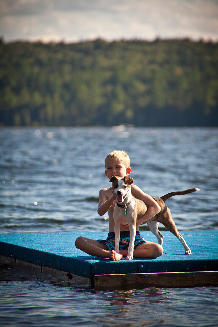 Boy With Dog on Floating Dock in Lake