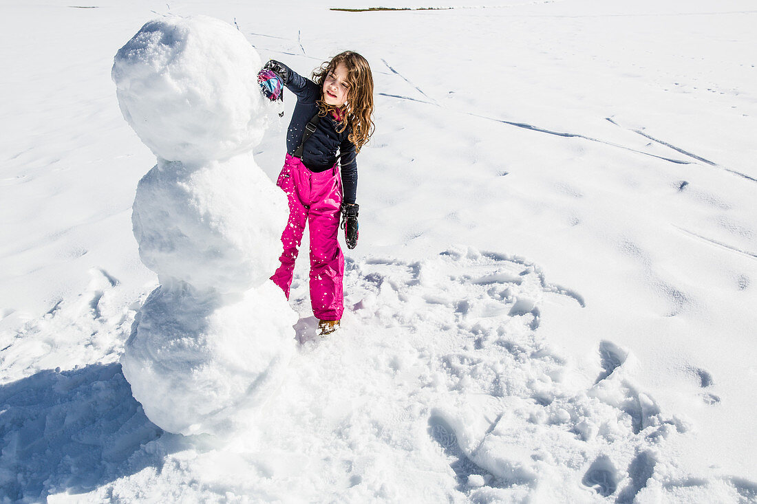 Mädchen baut einen Schneemann im Winter, Pfronten, Allgäu, Bayern, Deutschland