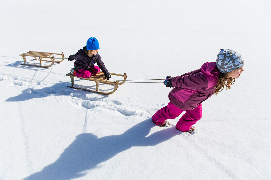 Girl pulling boy on his sled, Pfronten, Allgaeu, Bavaria, Germany