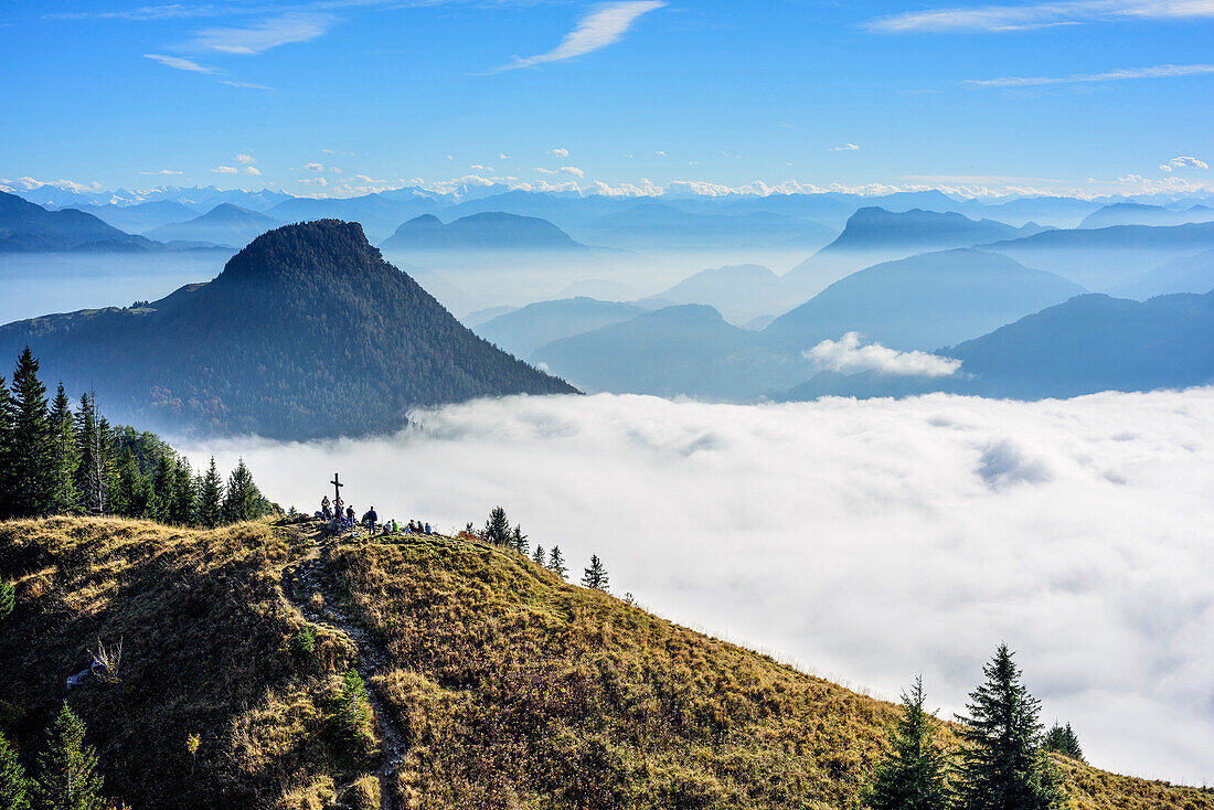 Wanderer stehen am Gipfel des Heuberg, Nebelmeer im Inntal, Kranzhorn und Pendling im Hintergrund, Blick von der Wasserwand, Wasserwand, Heuberg, Chiemgau, Chiemgauer Alpen, Oberbayern, Bayern, Deutschland