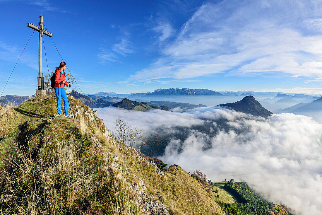 Woman hiking standing at Kitzstein, fog in valley of Inn, Kaiser range and Kranzhorn in background, Kitzstein, Chiemgau, Chiemgau Alps, Upper Bavaria, Bavaria, Germany