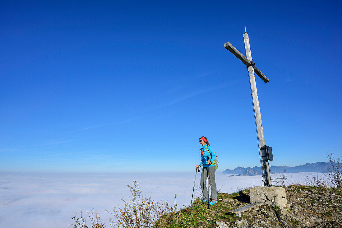 Frau beim Wandern steht am Gipfel des Großen Riesenkopf und blickt auf Nebelmeer, Großer Riesenkopf, Mangfallgebirge, Bayerische Alpen, Oberbayern, Bayern, Deutschland