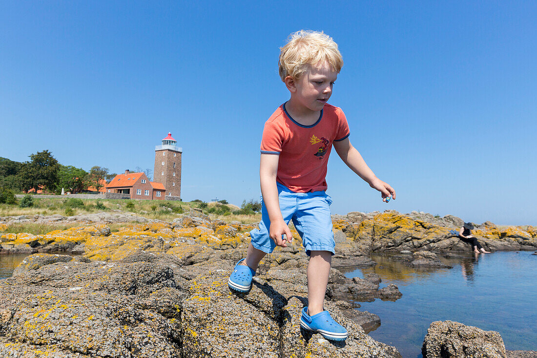 Junge, 5 Jahre, springt über die Felsen am Strand bei Hullehavn Camping, am Leuchtturm von Svaneke, Sommer, dänische Ostseeinsel, Ostsee, MR, Insel Bornholm, Svaneke, Dänemark, Europa
