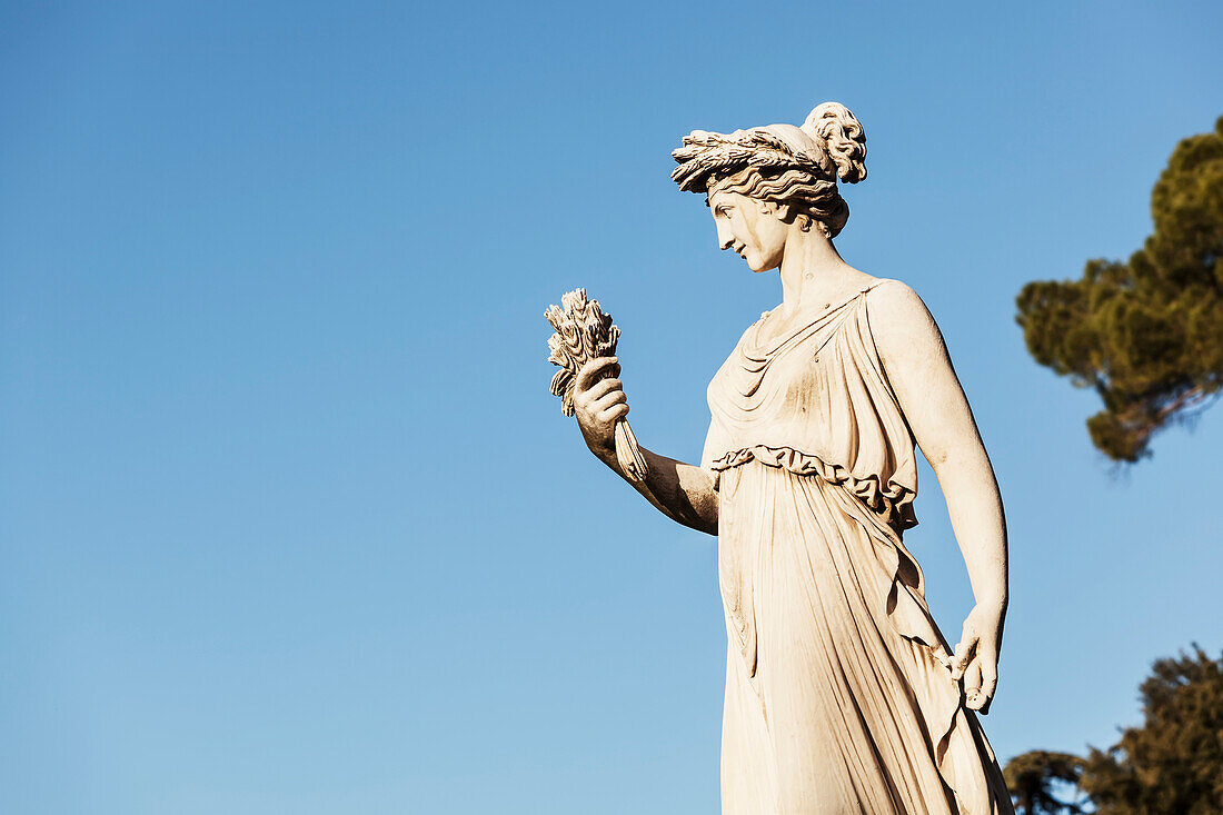 Statue of female figure against a blue sky, Rome, Italy