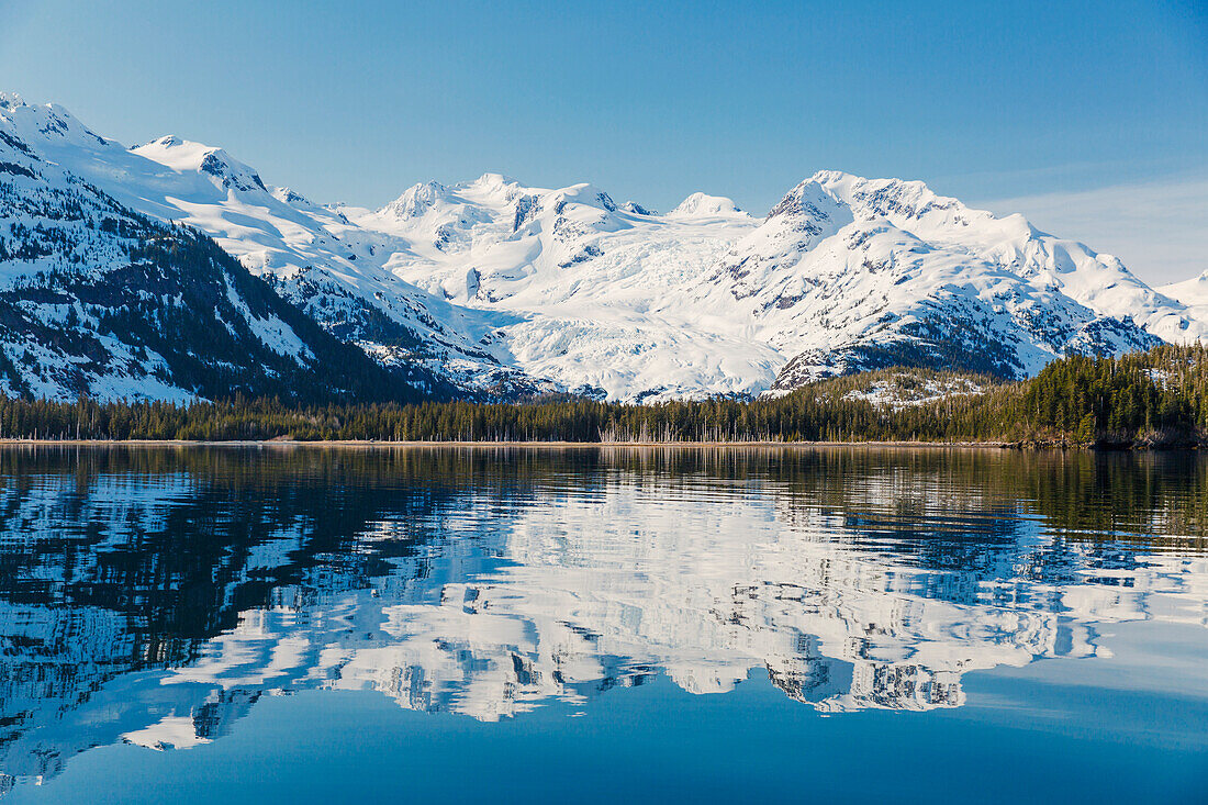 A glacier hangs in a valley below jagged snow covered peaks in Kings Bay, Prince William Sound, Whittier, Alaska, United States of America