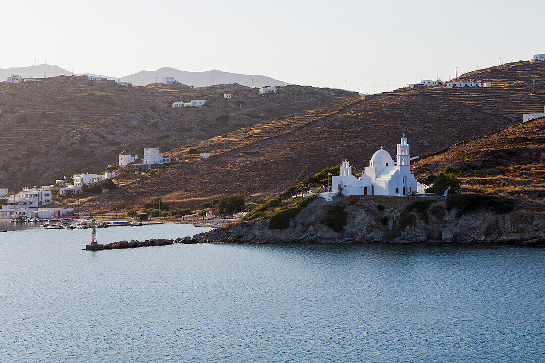 Port and white church on a cliff at the water's edge, Ios, Greece