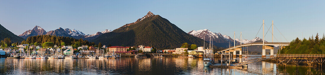Downtown Sitka and the O'Connell bridge on a clear summer evening, Sitka harbour and docked fishing boats in the foreground, the Sisters Mountains with snow on the peaks in the background, Sitka, Alaska, United States of America