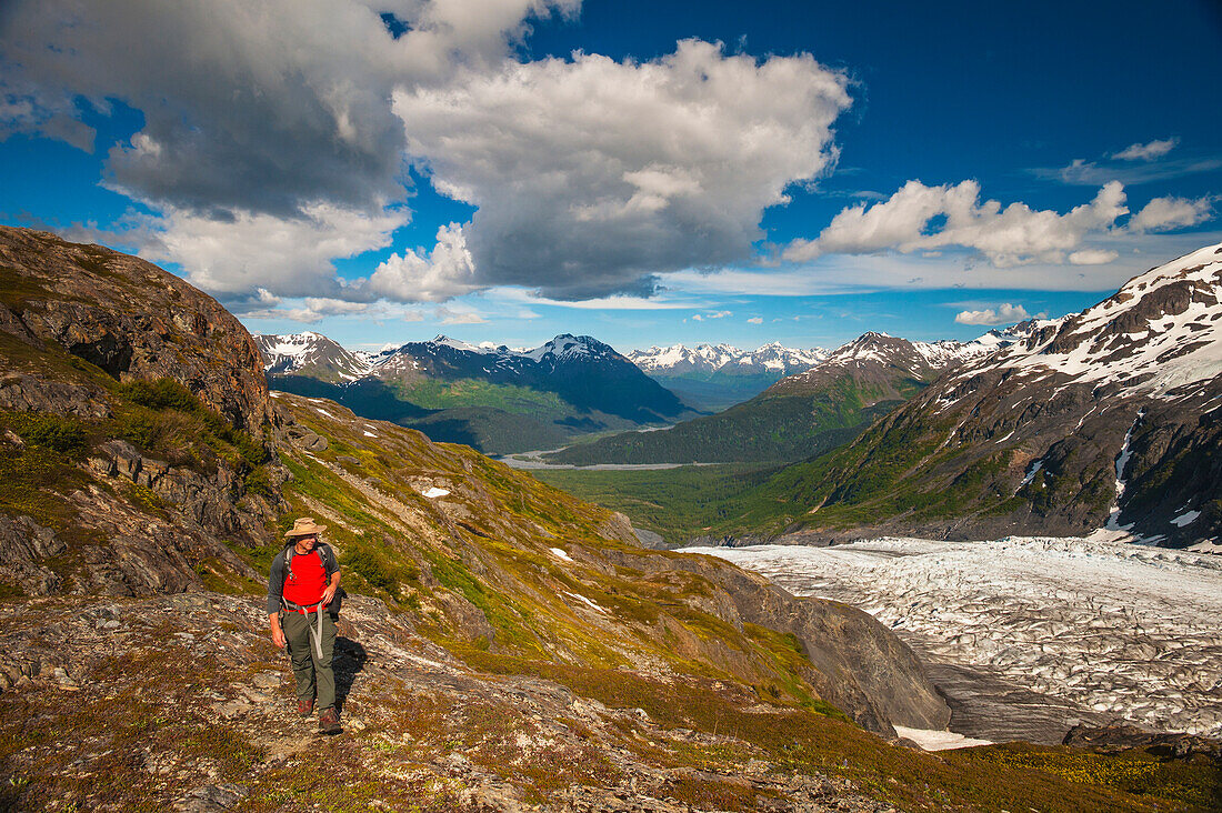 A man hiking near the Harding Icefield Trail with the Chugach Mountains and the Resurrection Valley in the background, Kenai Fjords National Park, Southcentral Alaska