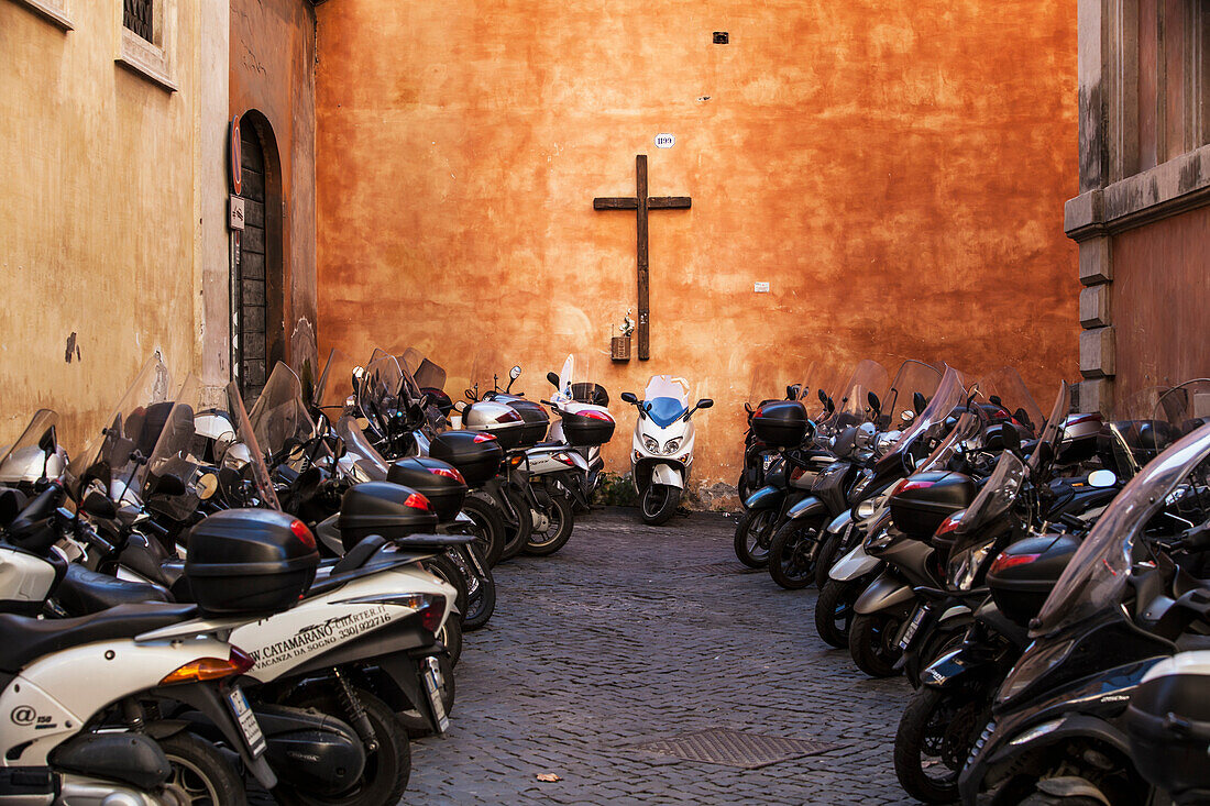Motorcycles parked outside a church with a  cross on the wall, Rome, Italy