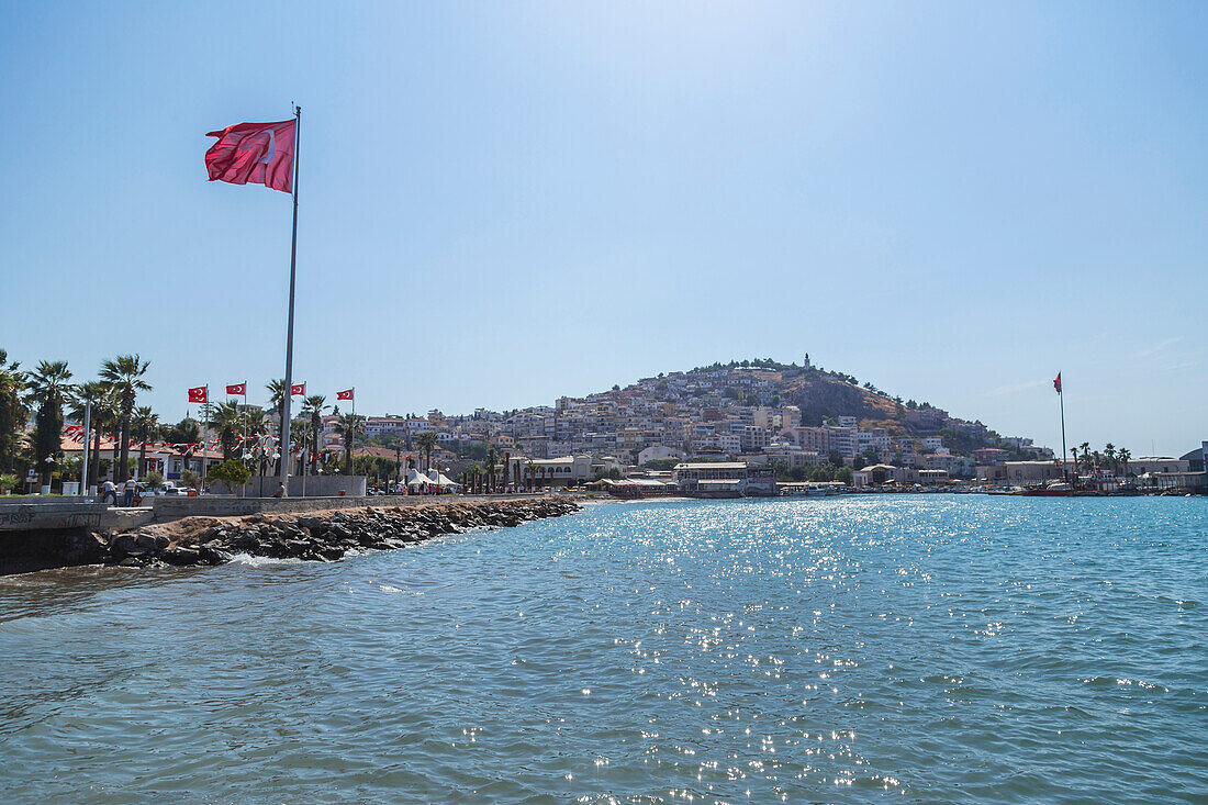 The Turkish flag flies in a blue sky on a sunny day next to the Mediterranean sea, Kusadasi, Izmir, Turkey