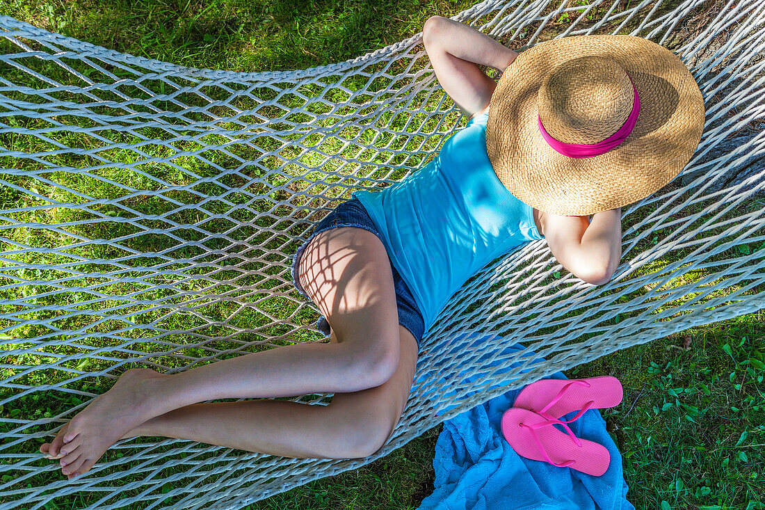 Girl resting in hammock under sun hat, Ontario, Canada