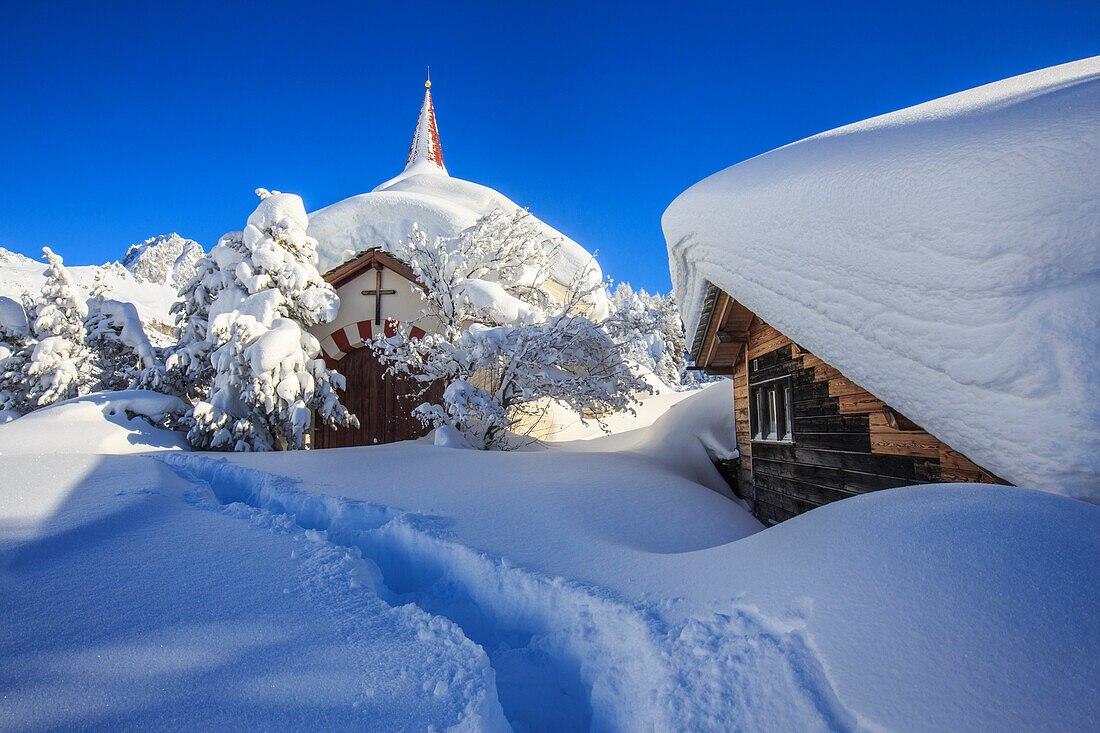 The small church and the house submerged by snow after a heavy snowfall in Maloja, Engadine, Graubunden Grisons Canton, Switzerland, Europe