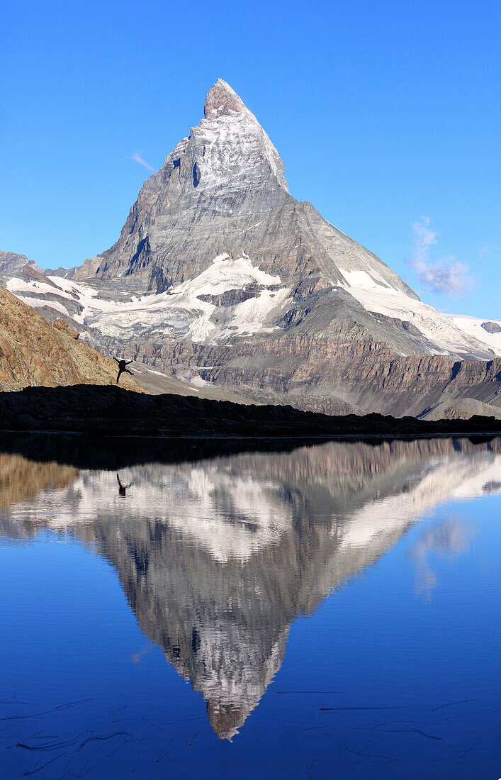 Hiker admiring the Matterhorn reflected in Lake Stellisee, Zermatt, Canton of Valais, Pennine Alps, Swiss Alps, Switzerland, Europe
