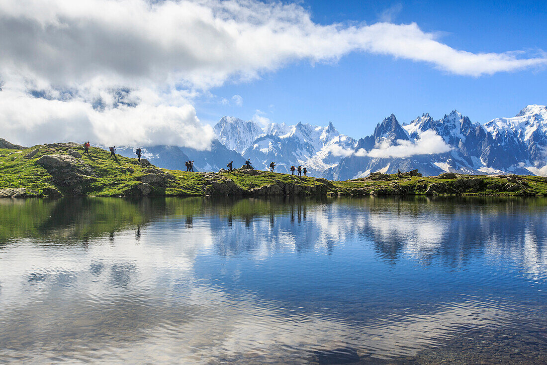 Low clouds and mist around Grandes Jorasses and Mont Blanc while hikers proceed on Lac De Cheserys, Haute Savoie, French Alps, France, Europe