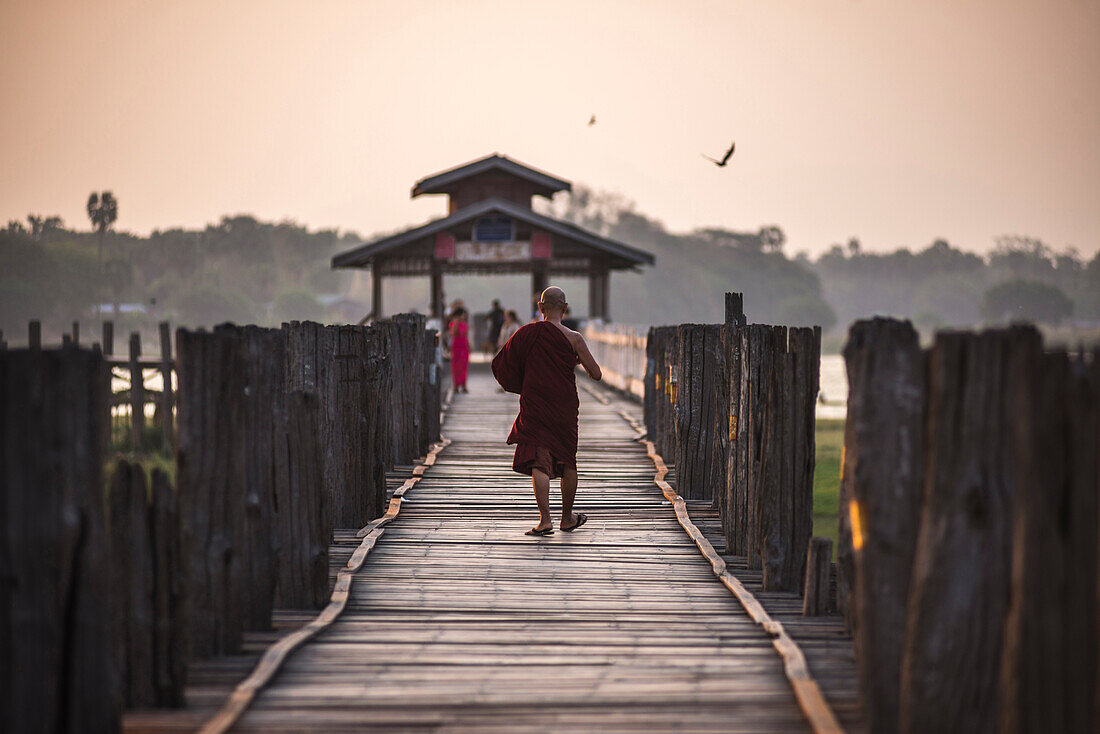 Buddhist Monk on U Bein Teak Bridge at sunrise, Mandalay, Mandalay Region, Myanmar Burma, Asia