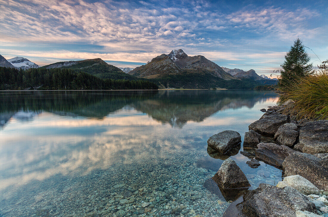 Pink sky at dawn illuminates the peaks reflected in Lake Sils, Engadine, Canton of Graubunden, Switzerland, Europe